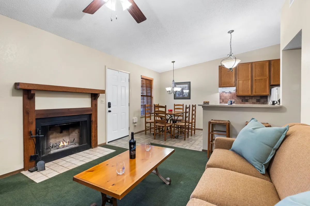 An open-plan interior where a fireplace, dining table, and sofa are visible in one inviting space. The layout creates a seamless transition between living, dining, and relaxation areas, capturing the easy flow and shared moments described in the section.