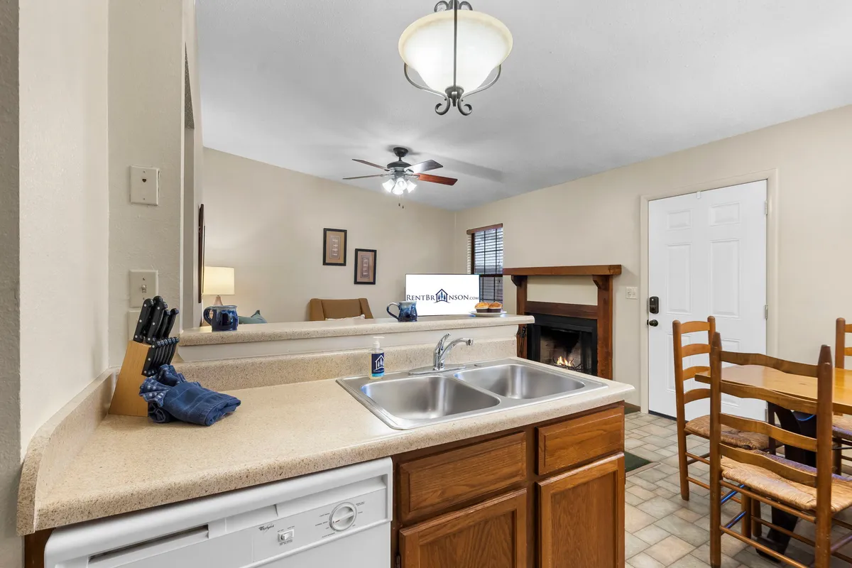 A cozy, inviting interior featuring a dining table, kitchen sink, a warm fireplace, and soft lighting. The setting exudes comfort and warmth, suggesting a space ideal for unwinding after a day outdoors.