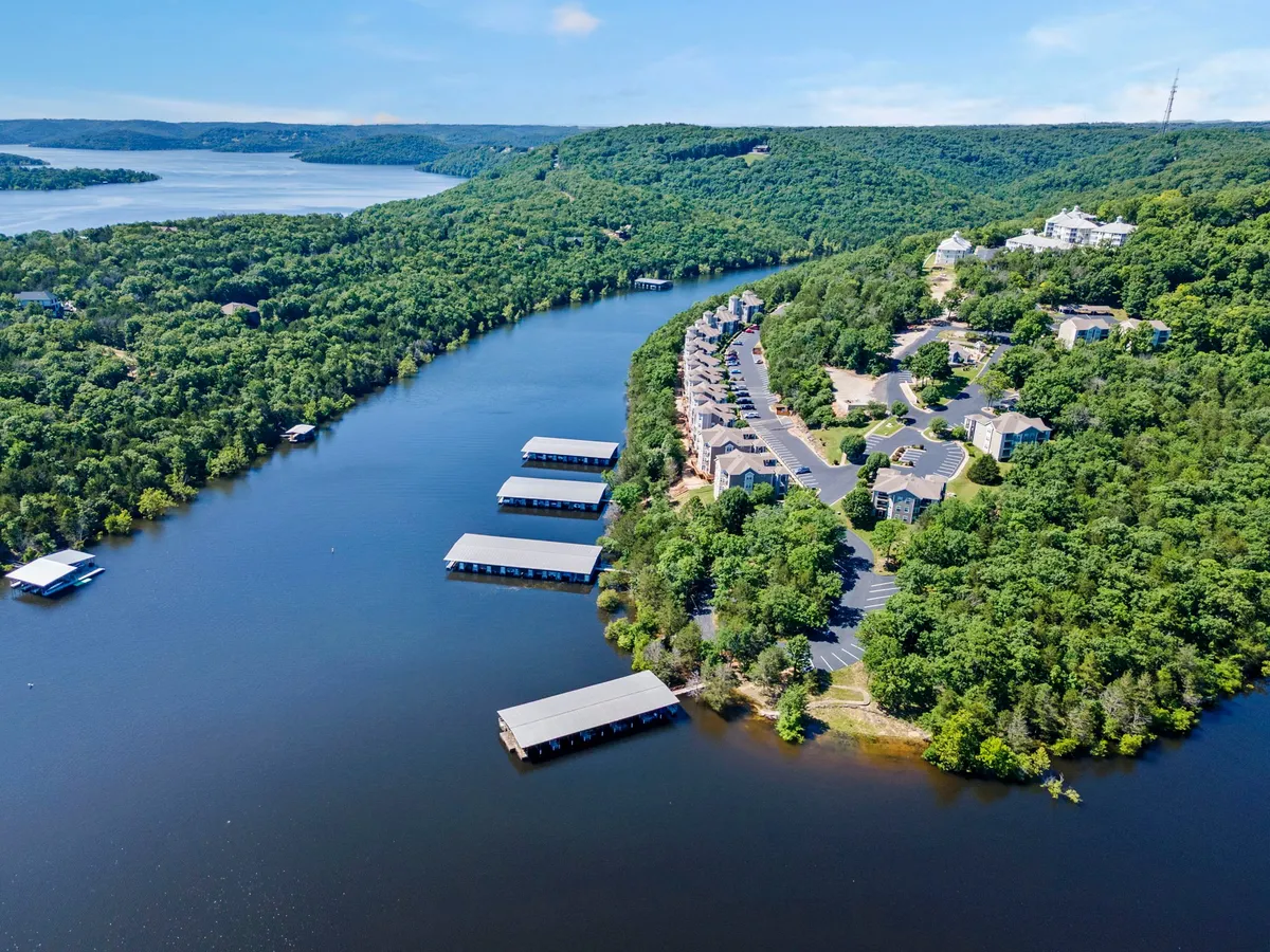 This view captures the expansive lake with a marina, rolling green hills, and a nearby residential area. The tranquil water reflects the sky, and the surrounding landscape transitions beautifully through the seasons, making it a perfect backdrop for boating, fishing, or enjoying autumn foliage.