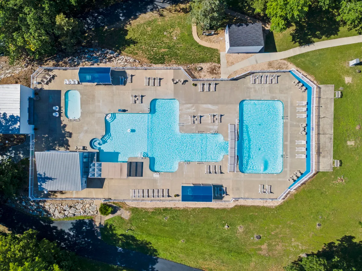 A cheerful exterior scene showcasing sparkling swimming pools surrounded by lounge chairs and lush greenery, with a poolside cabana providing shaded relaxation. Children are seen playing in the water, emphasizing the family-friendly, playful atmosphere.