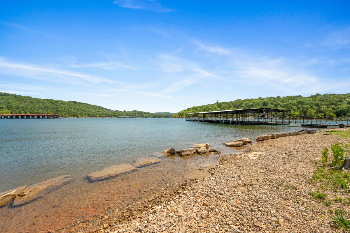 A tranquil view of Table Rock Lake features calm water stretching toward distant green hills, with a dock structure in the foreground. The scene exudes peace and hints at plentiful opportunities for boating, fishing, and lakeside picnics.