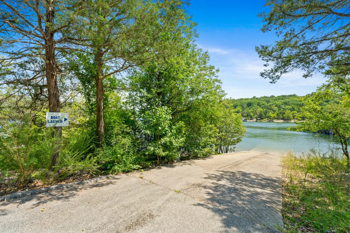 An inviting exterior shot of a boat launch area featuring a concrete ramp, clear signage, and lush greenery leading down to the lake. The scene suggests ease of access to boating and lakeside adventures, with tranquil water beckoning just beyond.